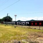 Black vinyl banner for a chrome shop hung on a fence outdoors, printed by Xenix Graphics