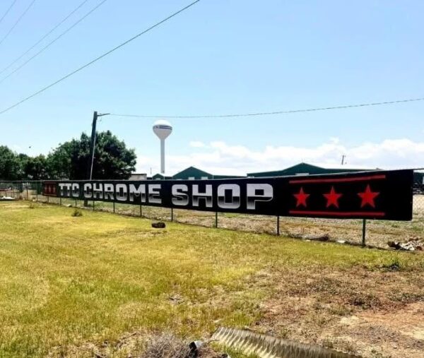 Black vinyl banner for a chrome shop hung on a fence outdoors, printed by Xenix Graphics