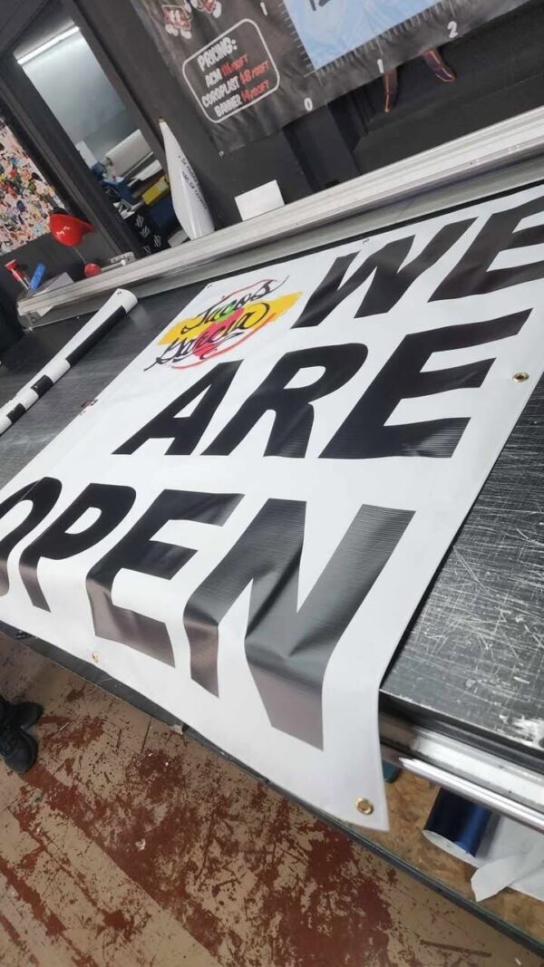 Large black-and-white We Are Open vinyl banner printed by Xenix Graphics